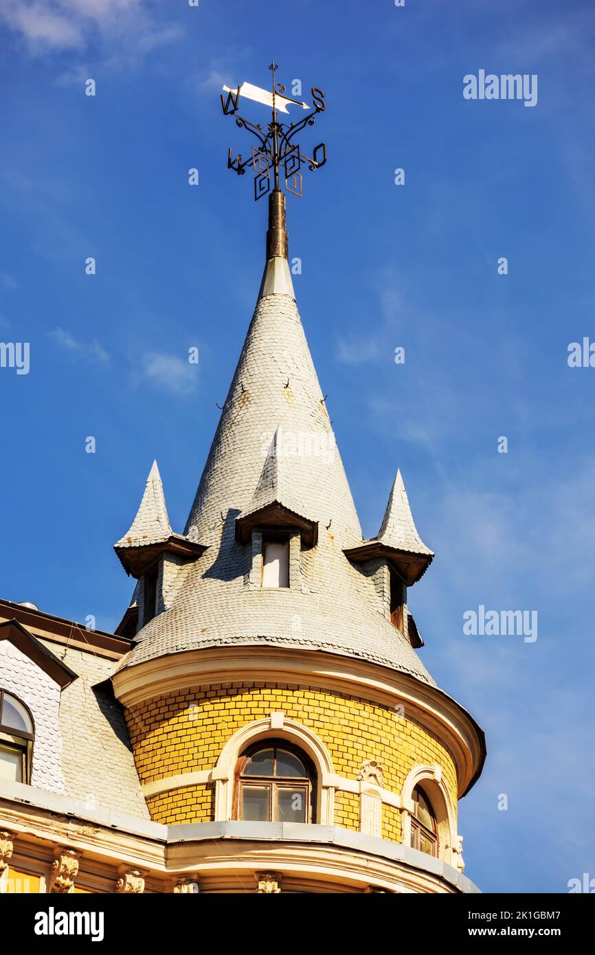 Eine Kirche mit einer gelben Mauer und einer spitzen Metallspitze mitten im Stadtzentrum Stockfoto