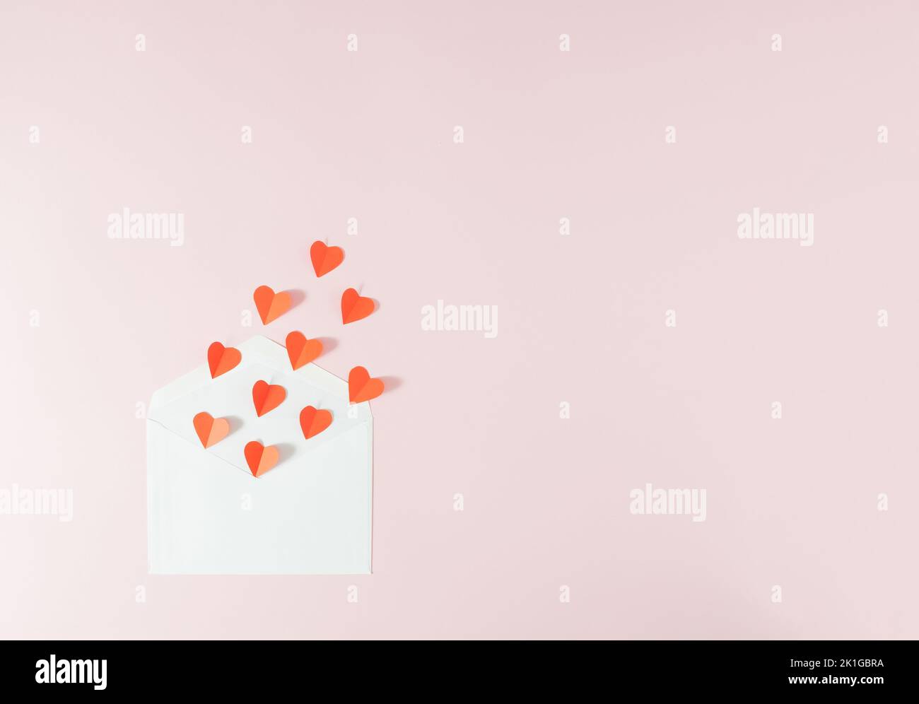 Rote Harts fliegen aus einem weißen Umschlag - Valentinstag-Liebeskarte. Minimalkonzept. Stockfoto