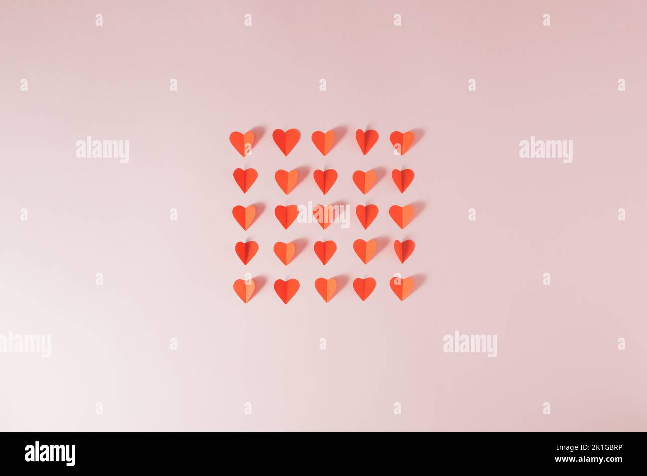 Rote Papierherzen auf einem hellrosa Hintergrund. Minimalkonzept. Stockfoto
