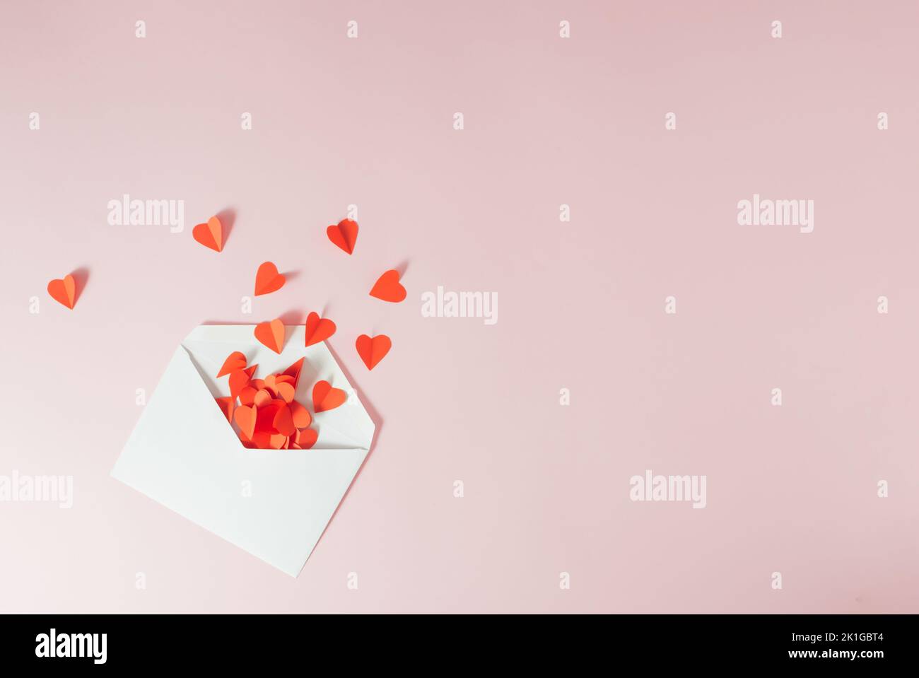 Rote Papierherzen fallen aus dem weißen Umschlag - Valentinskarte. Minimalkonzept. Stockfoto