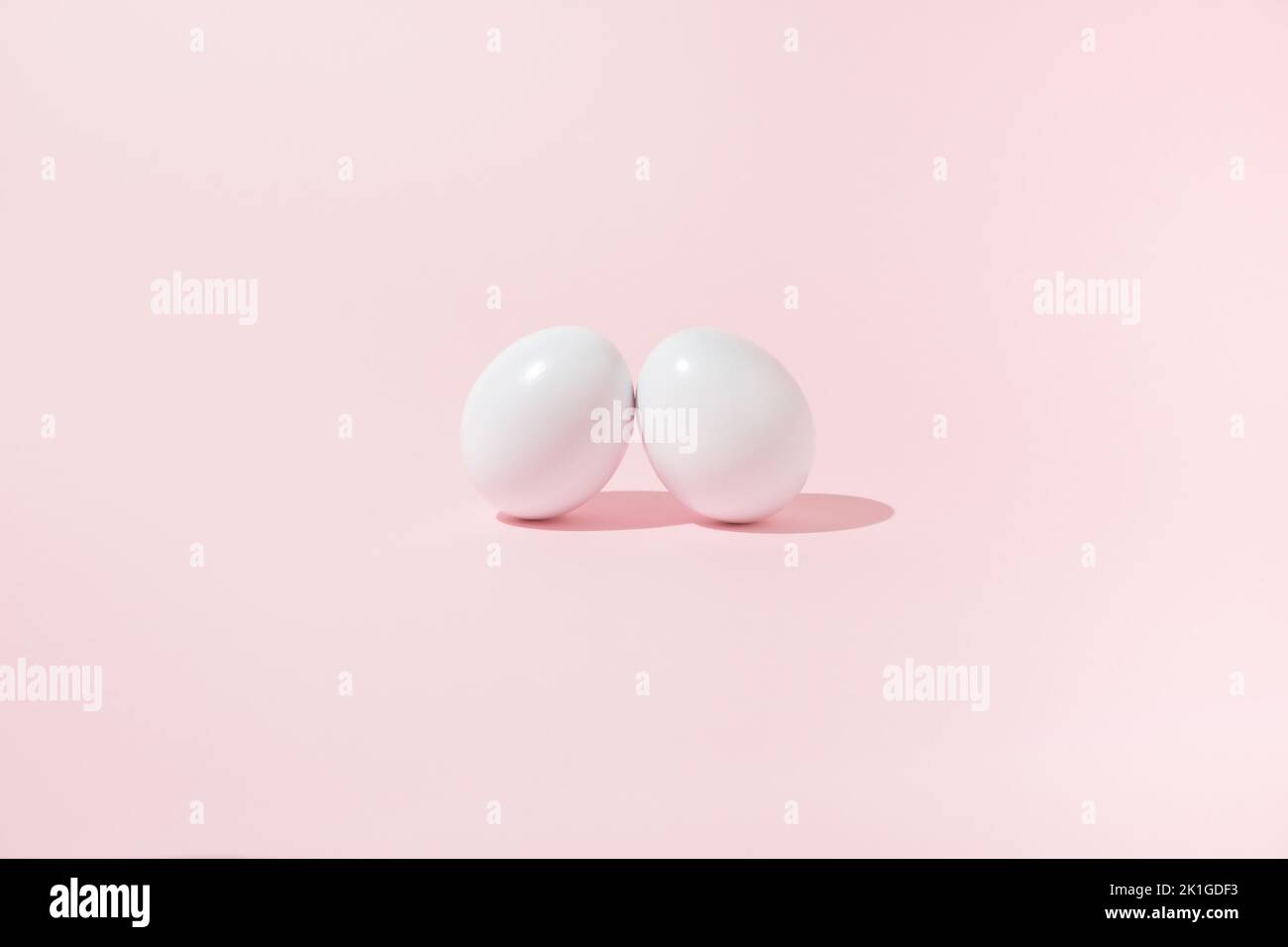 Osterszene mit zwei weißen Eiern, die sich auf pinkem Hintergrund anlehnen. Stockfoto