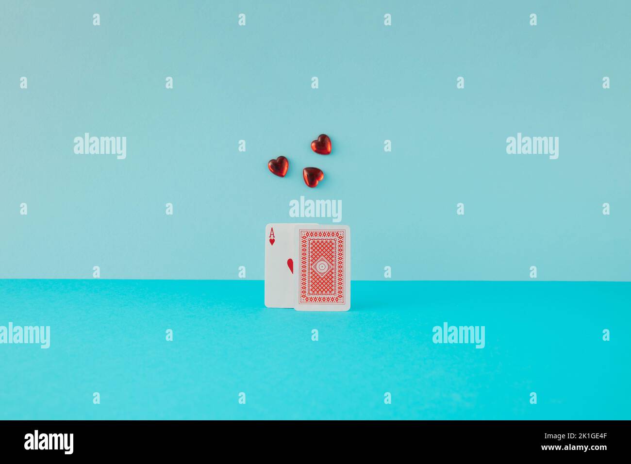 Zwei Spielkarten mit Herz-Ass und glasroten Herzen auf blauem Hintergrund. Minimalkonzept. Stockfoto
