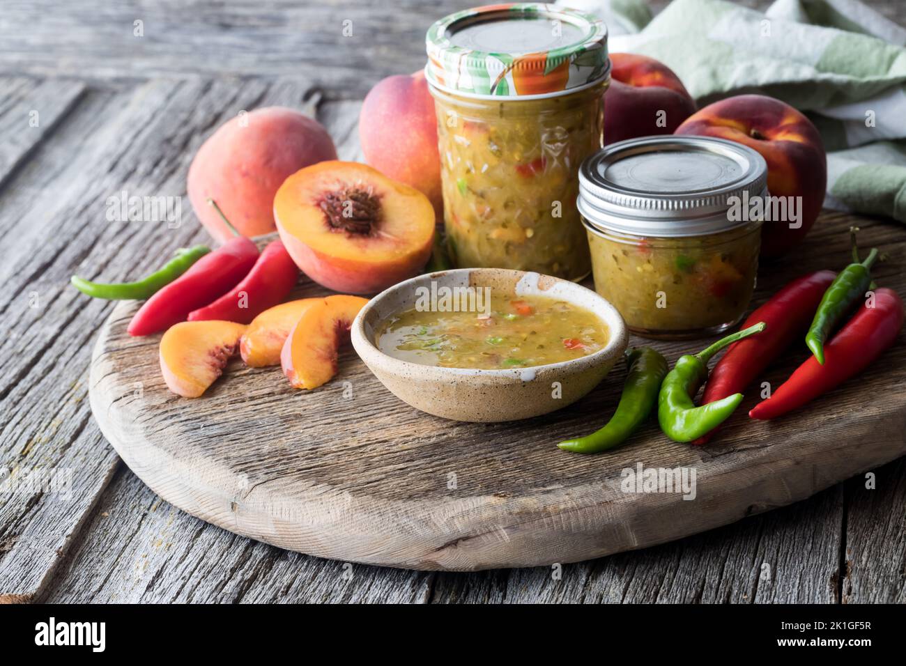 Gläser von Pfirsich und Paprika Salsa umgeben von Zutaten verwendet, um es zu machen. Stockfoto