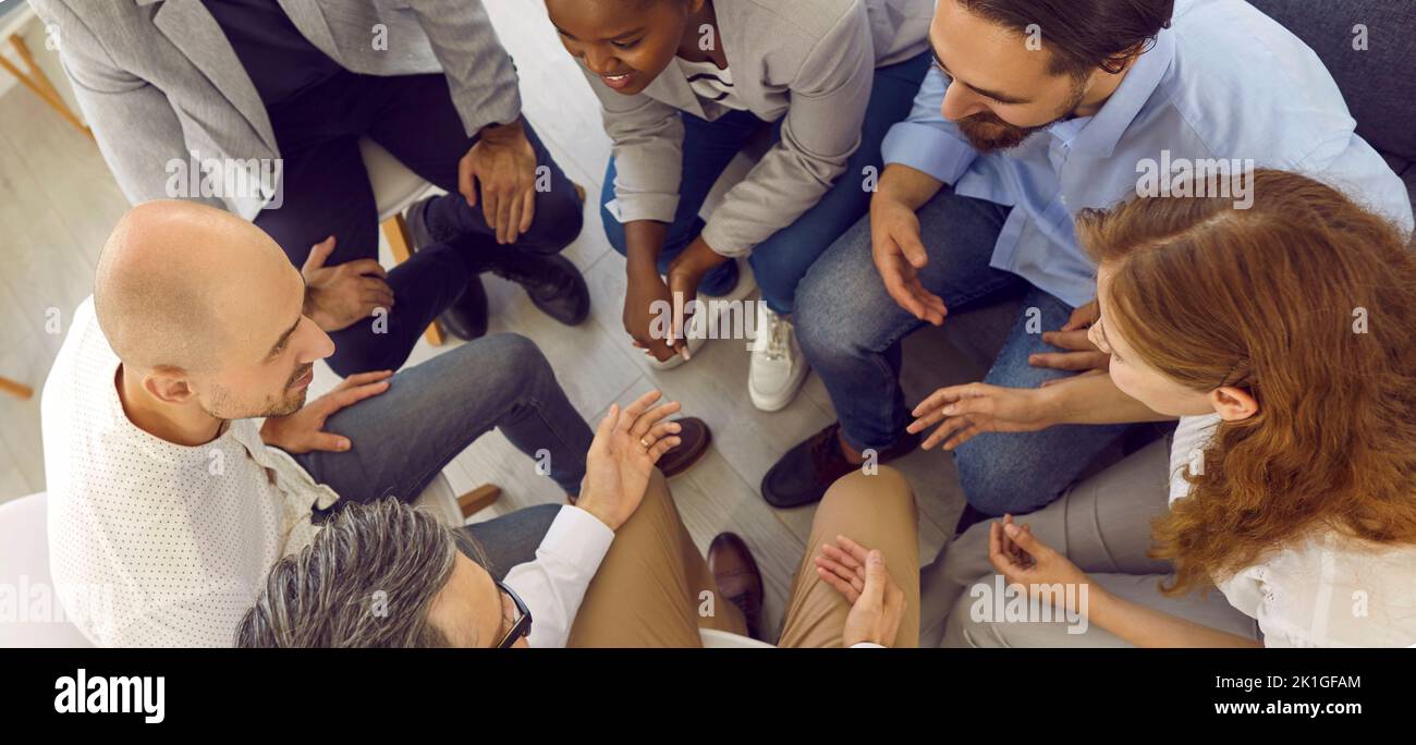 Ein fröhliches und freundliches Team von Bürokollegen sitzt im Kreis und plaudert während der Arbeitspause. Stockfoto