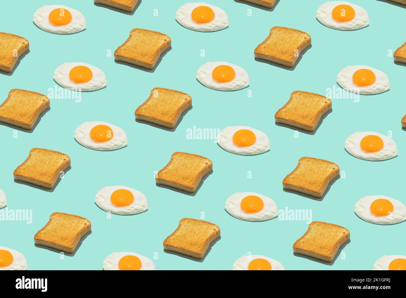 Nahtloses, kreatives Lebensmittelmuster. Spiegeleier und Toast auf blauem Hintergrund. Lustiges, farbenfrohes Frühstückskonzept. Stockfoto