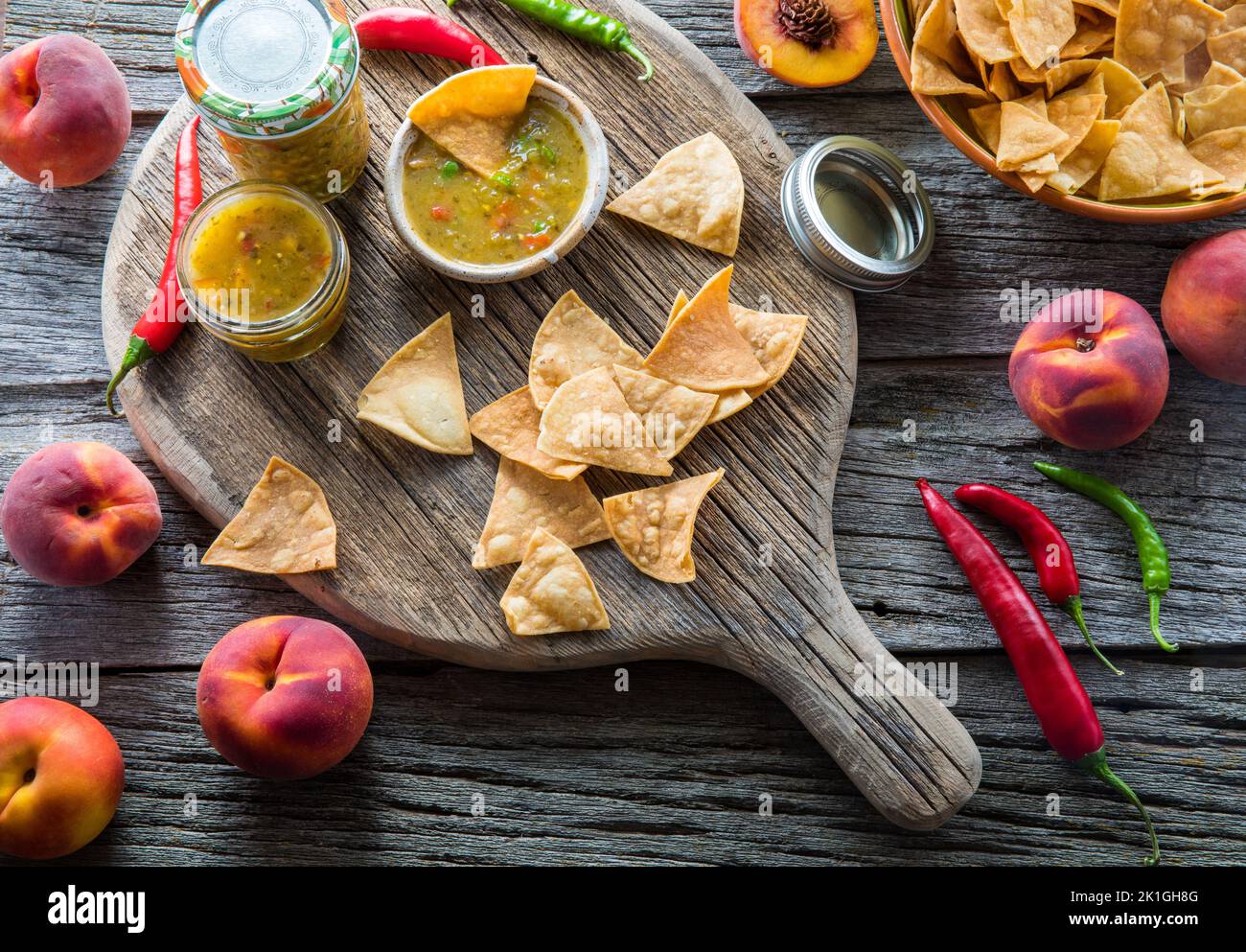 Peach- und Pfeffersalsa serviert mit Tortilla-Chips auf einem rustikalen Holzbrett. Stockfoto
