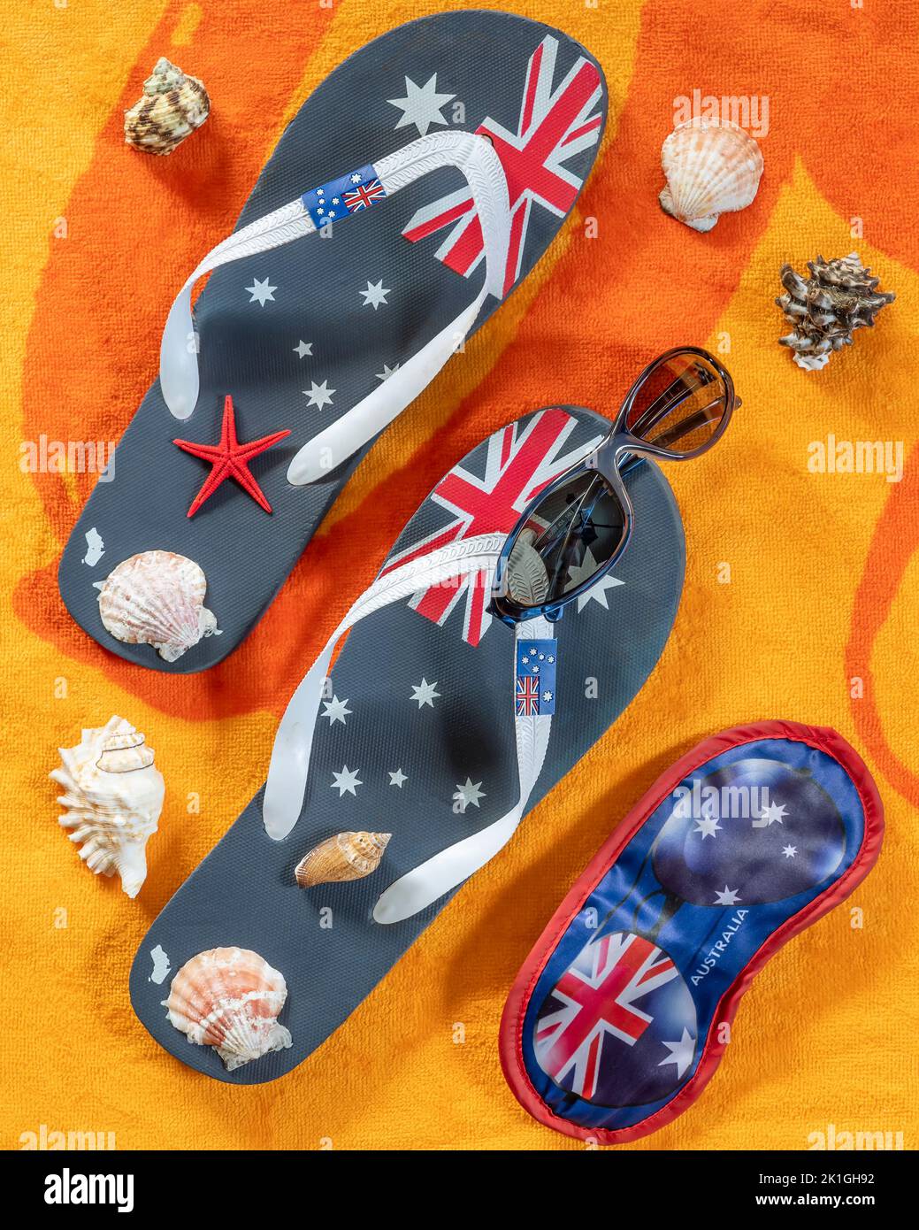 Augenmaske und Flip-Flops mit australischer Flagge, Muscheln und Sonnenbrille auf orangefarbenem und gelbem Hintergrund Stockfoto