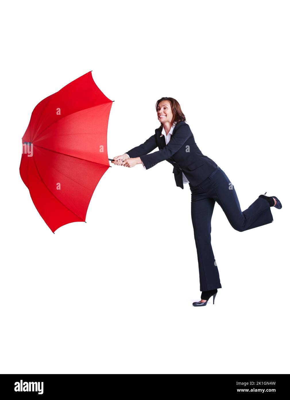 Ihren Regenschirm dem Wind zu verlieren. Studioaufnahme einer Geschäftsfrau, die sich auf einen Fuß lehnt und dabei einen Regenschirm hält. Stockfoto