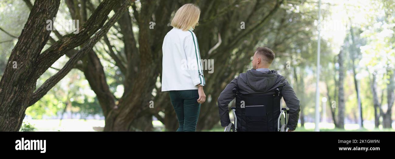 Frau und Mann im Rollstuhl gehen im Park Stockfoto