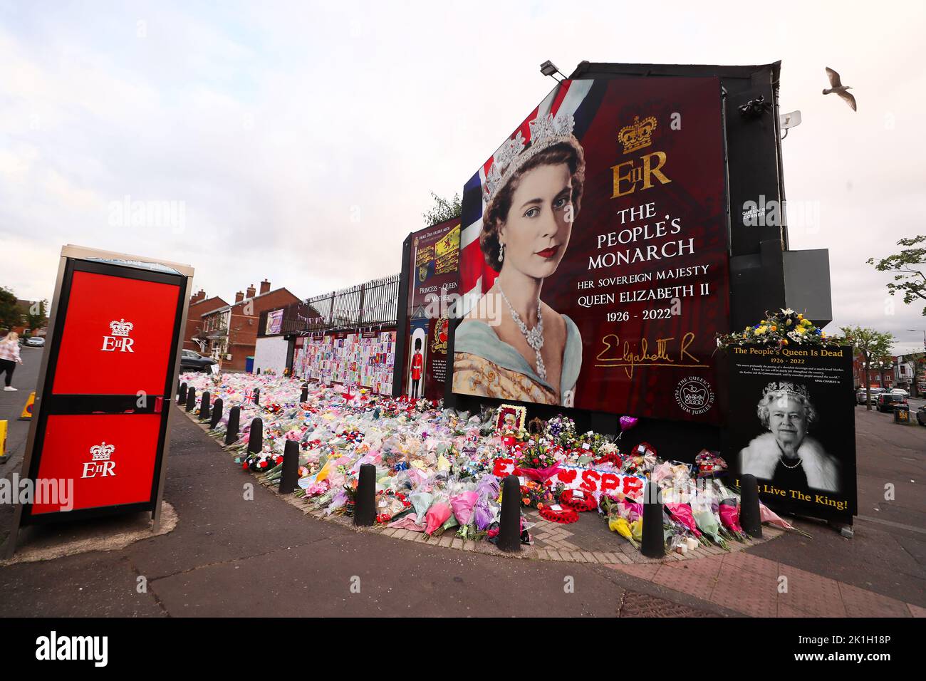 Nach dem Tod des britischen Monarchen legt man Blumen auf ein Wandgemälde, das Königin Elizabeth II. Auf der Shankill Road in Belfast darstellt. Stockfoto