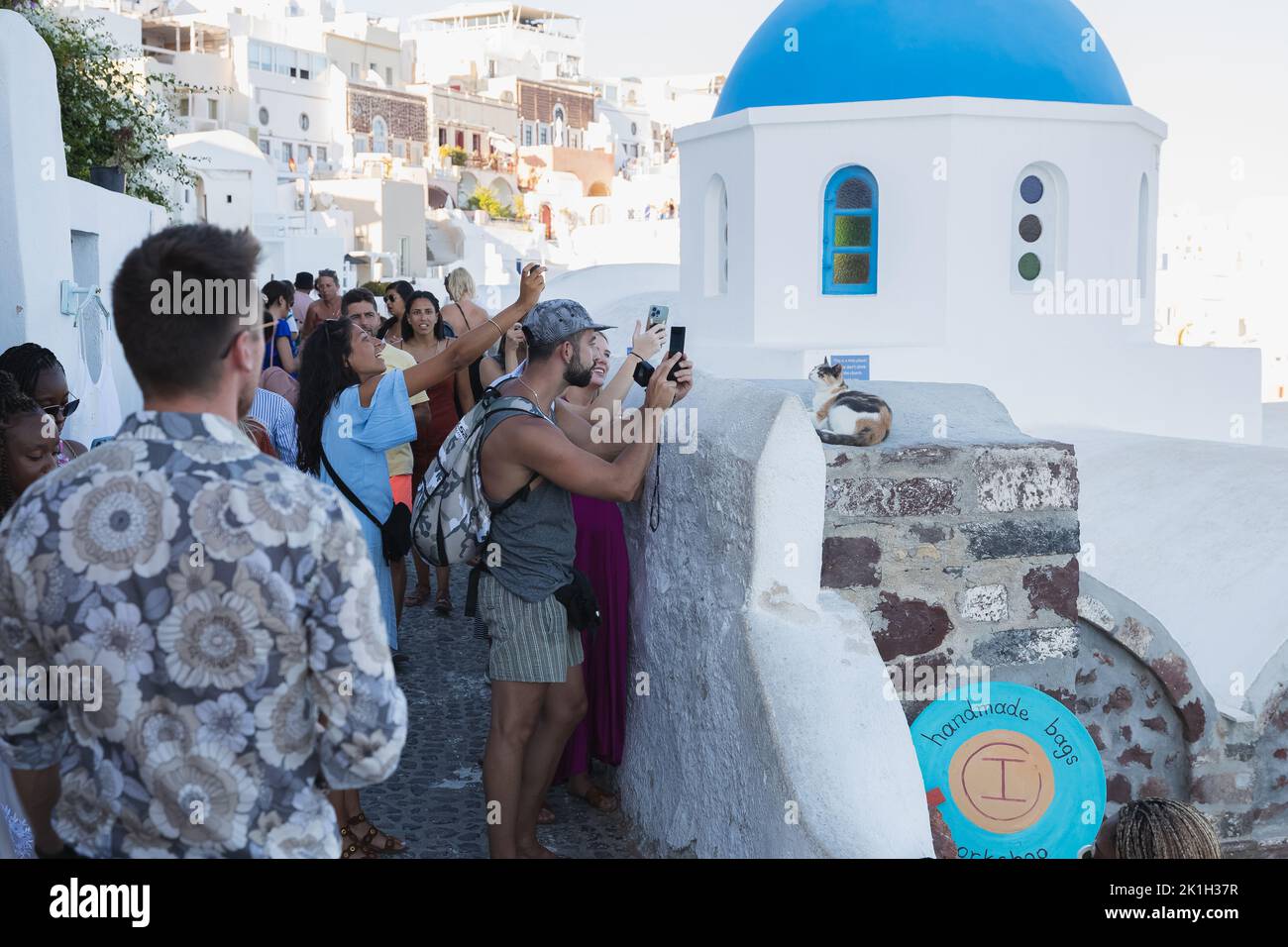 Oia, Griechenland - 9 2022. September: Enge, überfüllte und gezahnte Straßen in Oia, Santorini, gefüllt mit einer Menge Touristen mit Smartphone-Fotos Stockfoto