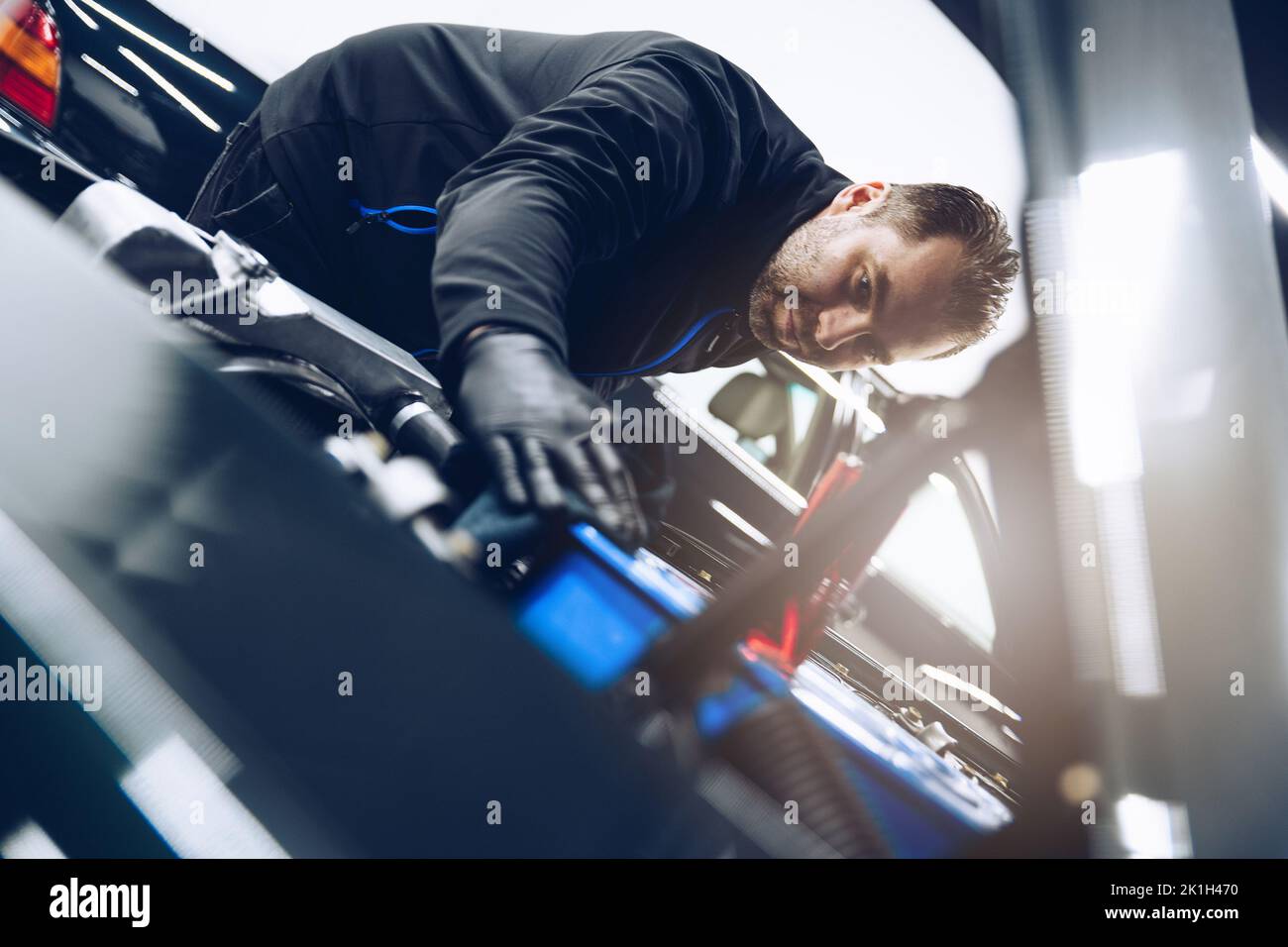 Automechaniker oder Autowascharbeiter reinigen den Automotor mit einem Tuch. Stockfoto