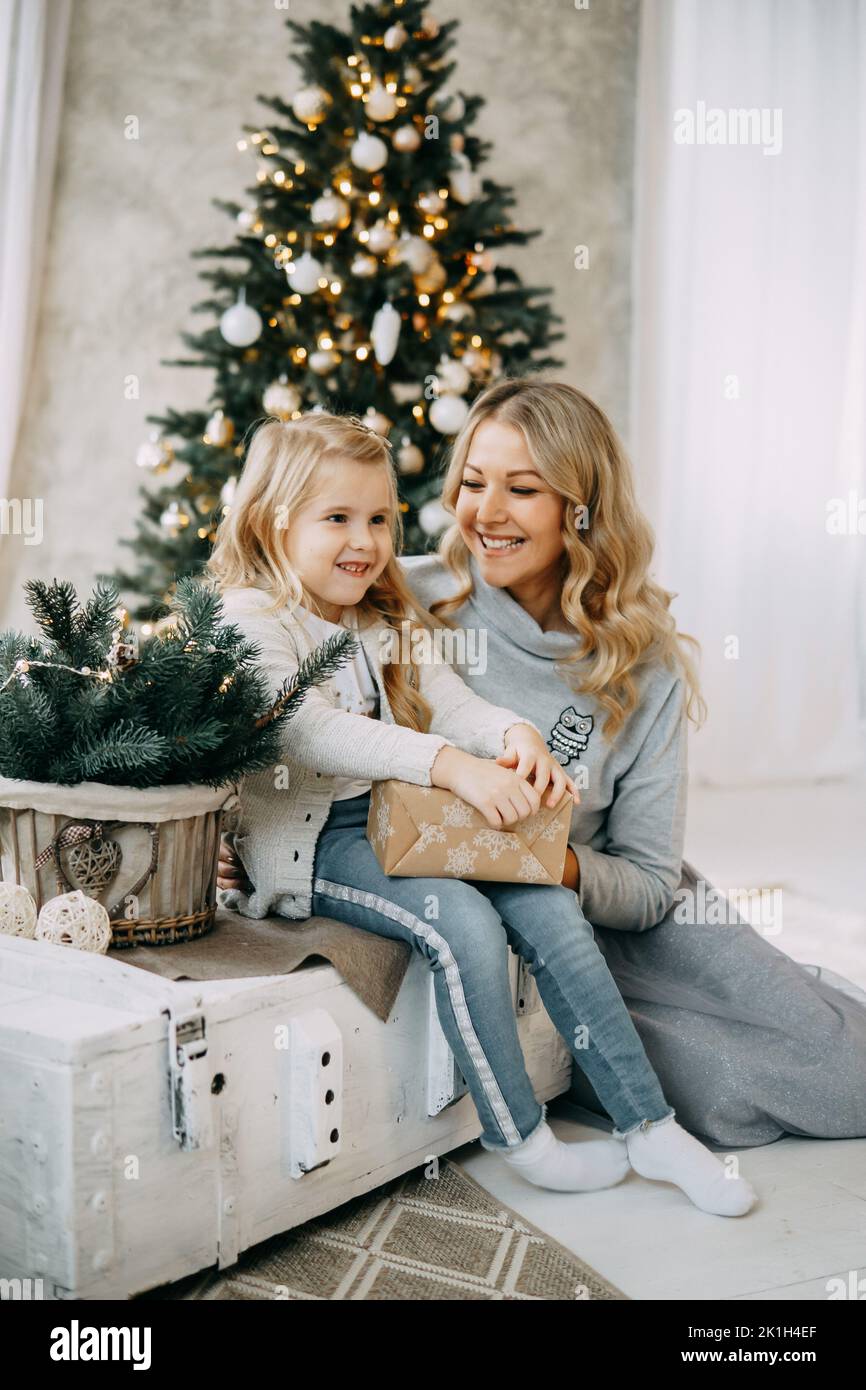 Glückliche Familie: Mutter und Tochter. Familie in einem hellen Neujahrsraum mit einem Weihnachtsbaum. Stockfoto