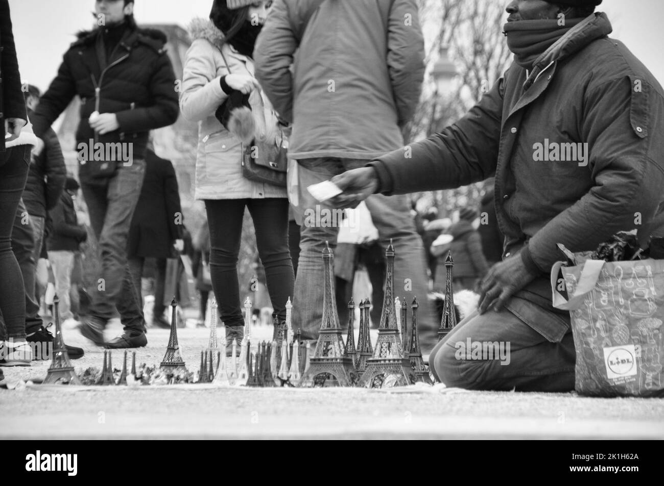 Ein Straßenverkäufer verkauft Miniatur-Eiffelturm auf dem Bürgersteig vor dem echten Eiffelturm in Paris Stockfoto