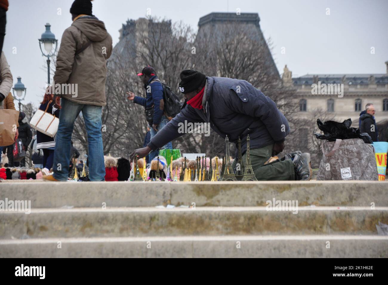 Ein Straßenhändler verkauft Miniatur-Eiffelturm auf dem Bürgersteig vor dem echten Eiffelturm in Paris Stockfoto