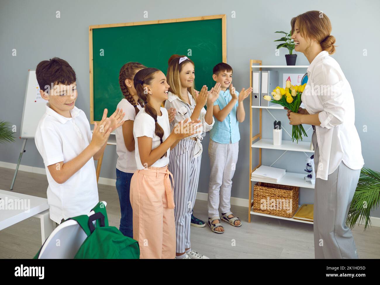 Fröhliche Schulkinder in der Schule gratulieren ihrer Lehrerin zum Internationalen Lehrertag. Stockfoto