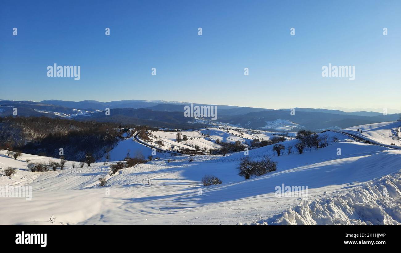 Eine schöne Aussicht von einem verschneiten Berg auf die anderen Bergketten mit dem blauen Himmel Stockfoto