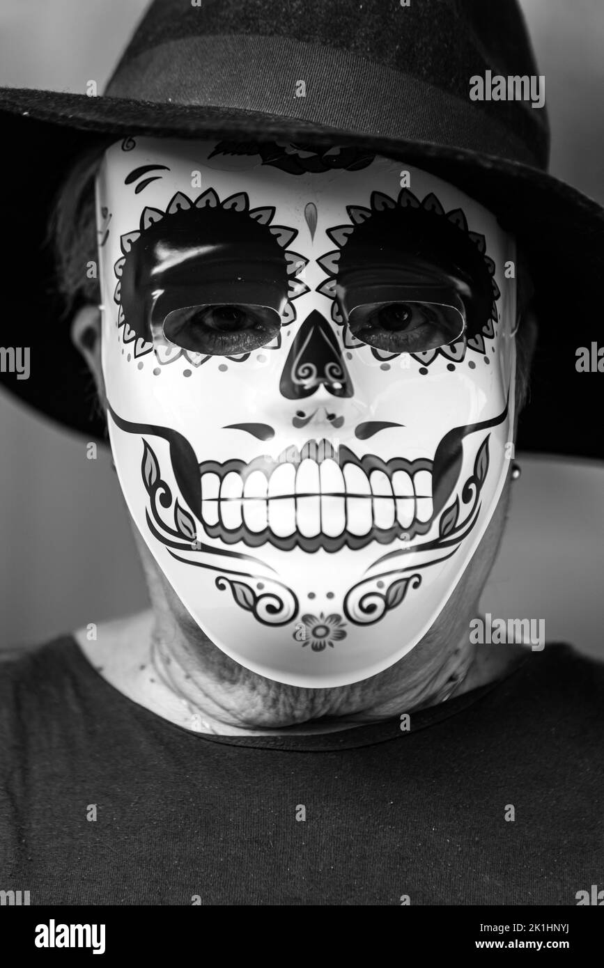 Schwarz-weißes Porträt einer älteren Dame mit catrina-Maske und Hut, die Halloween und All Souls' Day feiert, auf weißem Hintergrund. Feier, Stockfoto