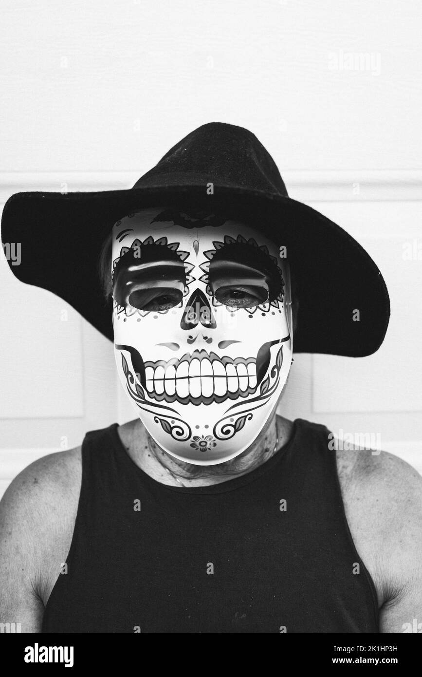 Schwarz-weißes Porträt einer älteren Dame mit catrina-Maske und Hut, die Halloween und All Souls' Day feiert, auf weißem Hintergrund. Feier, Stockfoto