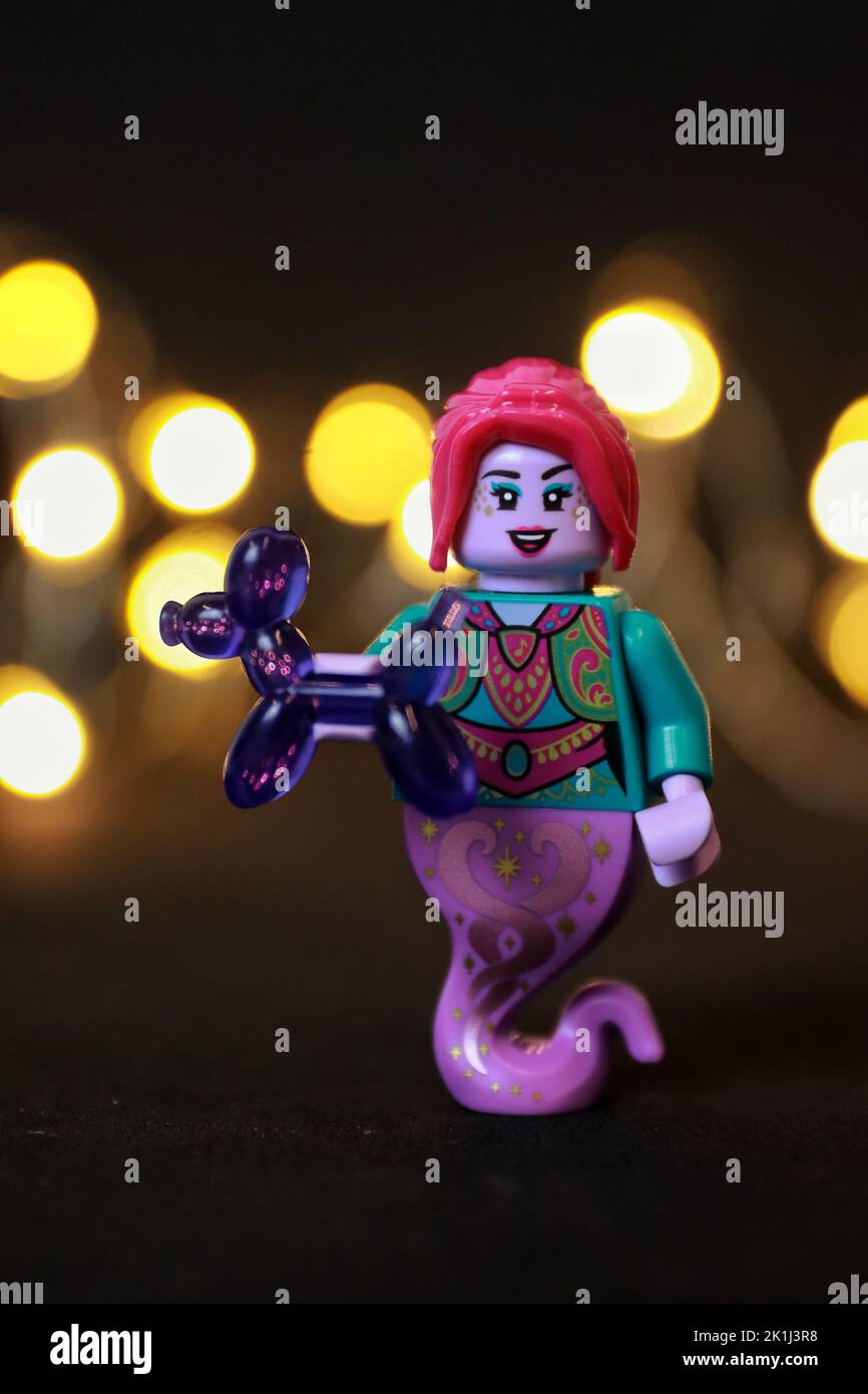 Eine weibliche Spielzeugfigur mit roten Haaren und Lippen, die ein violettes Ballontier hält Stockfoto