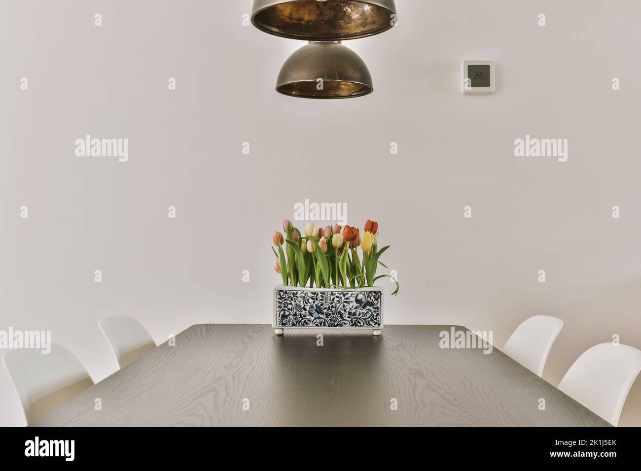 Holztisch mit Blumenvase unter schwarzer Pendelleuchte im modernen Wohnzimmer Stockfoto