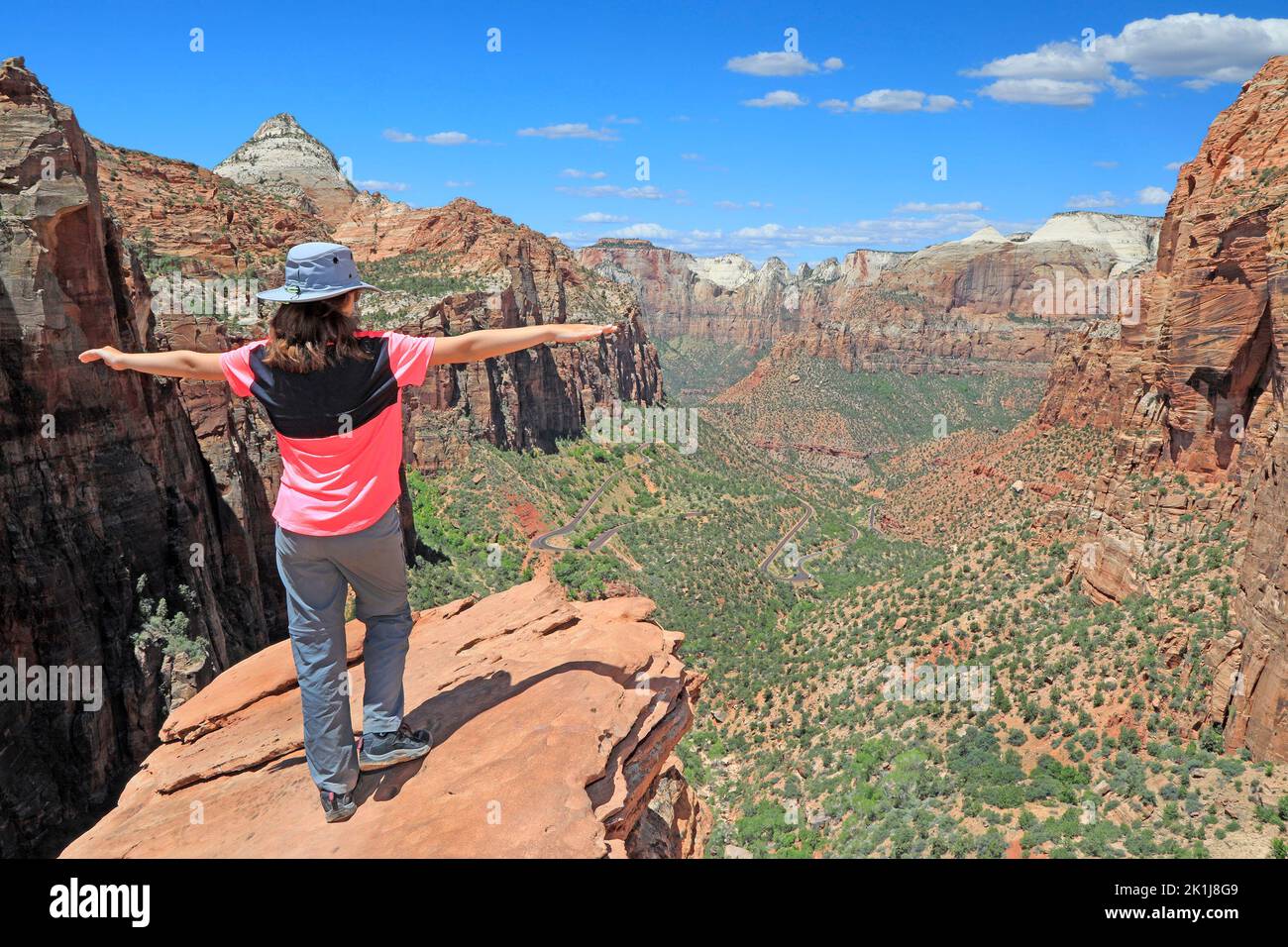 Junge Touristenfrau, die auf dem Bergrücken steht und die Landschaft des Zion Canyon in Utah, USA, bewundert Stockfoto