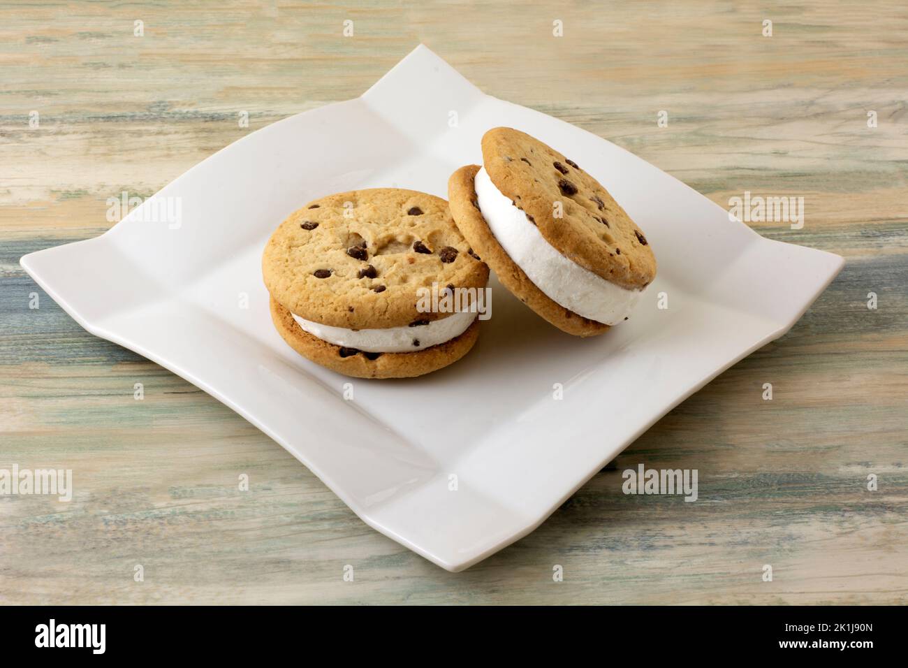 Zwei Schokoladenkekse-Vanilleeis-Sandwiches auf weißem Dessertteller Stockfoto