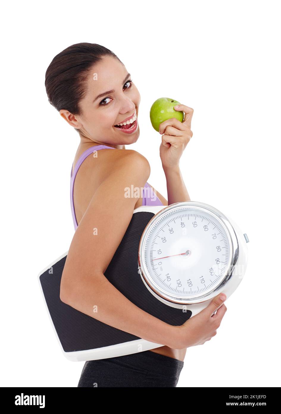 Ein gesunder Lebensstil bedeutet, dass Gewichtsverlust einfach ist. Studioaufnahme einer attraktiven jungen Frau in Turnkleidung mit Apfel- und Waage. Stockfoto