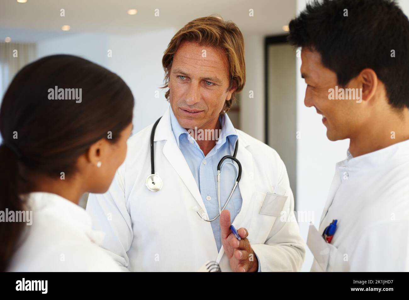 Rücksprache mit seinen medizinischen Kollegen. Drei medizinische Fachkräfte, die bei der Arbeit ein Gespräch führen. Stockfoto