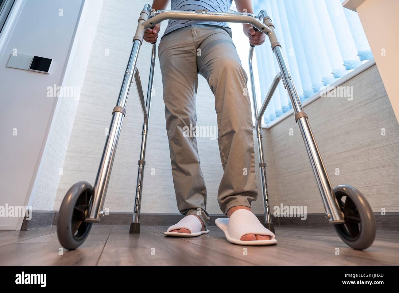 Ein kranker Mensch bewegt sich mit Hilfe spezieller Wanderer. Probleme mit dem Bewegungsapparat. Das Konzept der Rehabilitation. Restaurative Verfahren. Stockfoto
