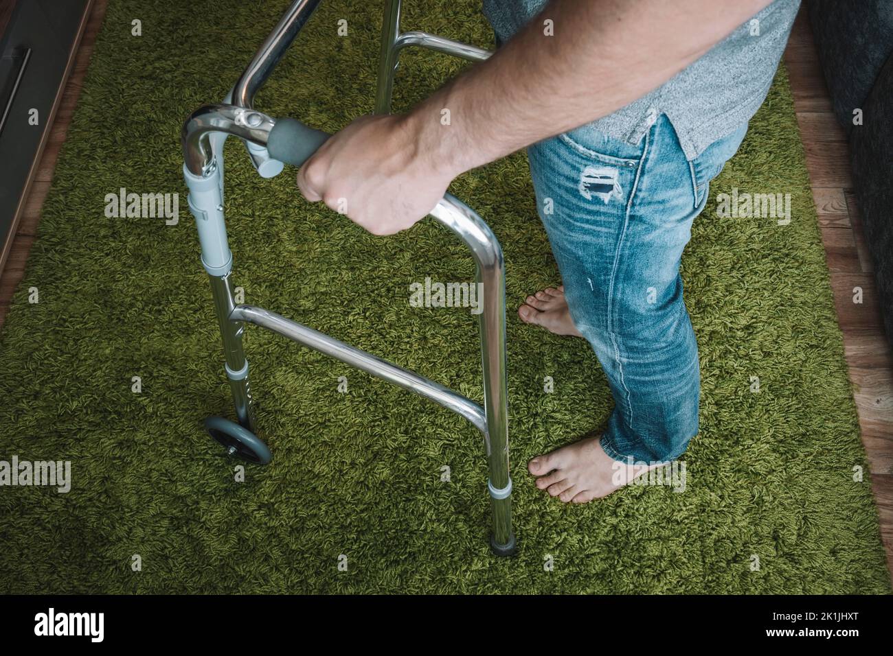 Ein kranker Mensch bewegt sich mit Hilfe spezieller Wanderer. Probleme mit dem Bewegungsapparat. Das Konzept der Rehabilitation. Restaurative Verfahren. Stockfoto