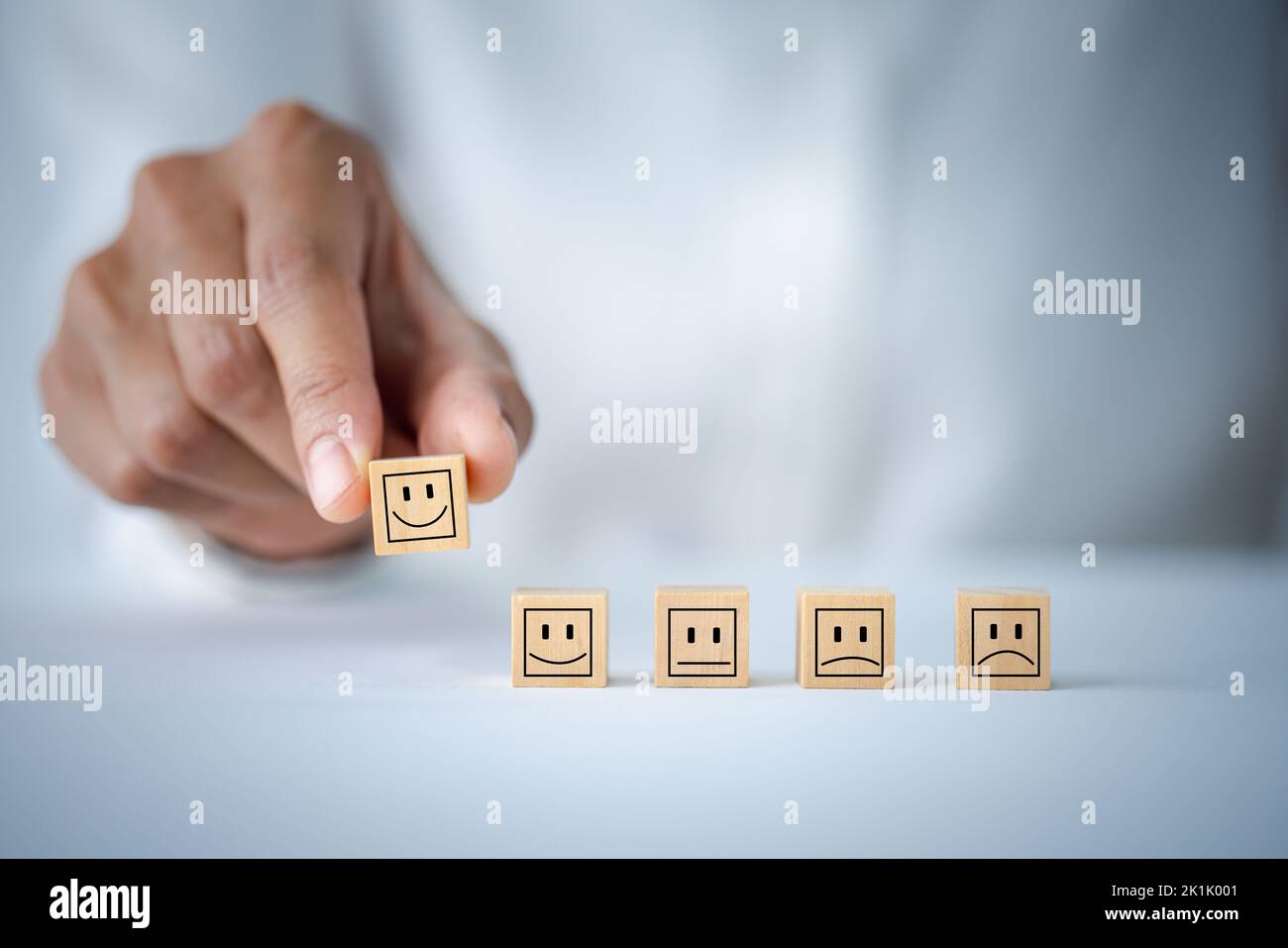 Kundendienst- und Zufriedenheitskonzept, Kundenhand wählen Smiley Face Icon auf Holzwürfel, Service Rating, Zufriedenheitskonzept. Stockfoto