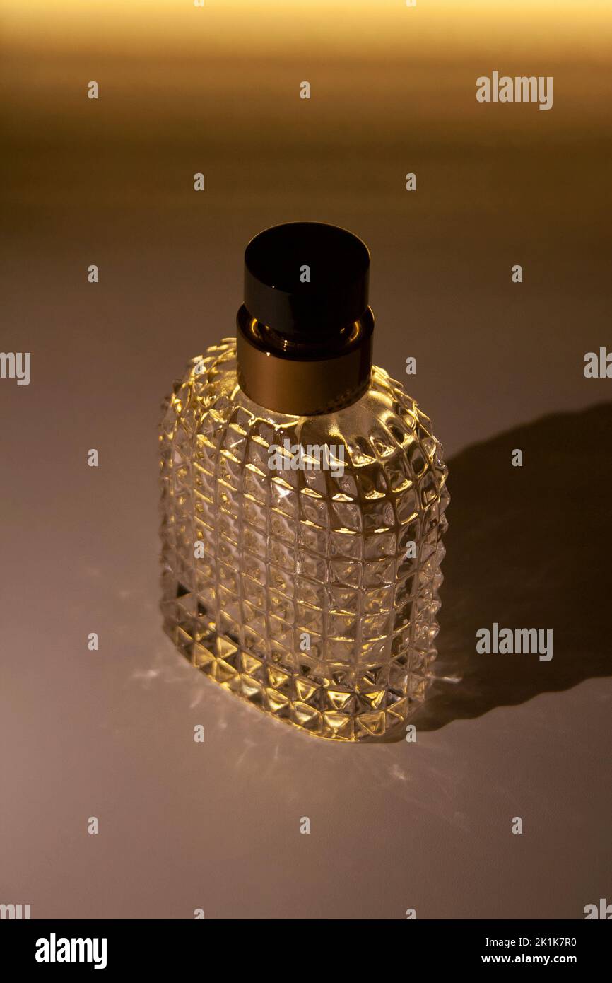 Strukturierte Parfümflasche aus Glas isoliert mit glühender Beleuchtung auf dem Hintergrund Stockfoto