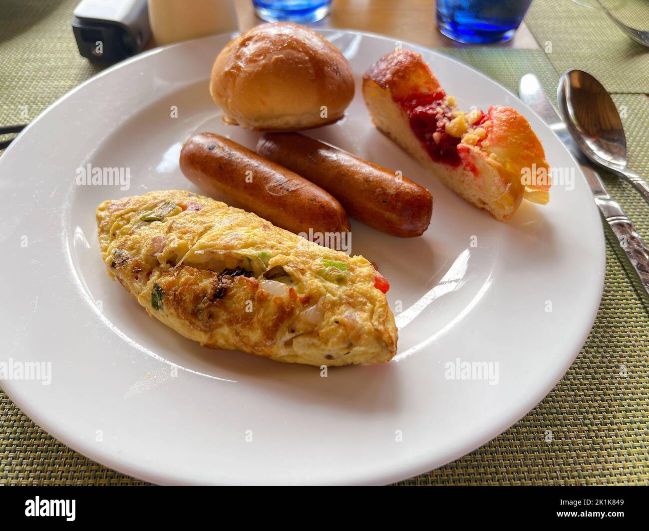 Ein gesunder Frühstücksteller mit Eieromelett, Würstchen und Brot auf einem weißen Teller. Stockfoto