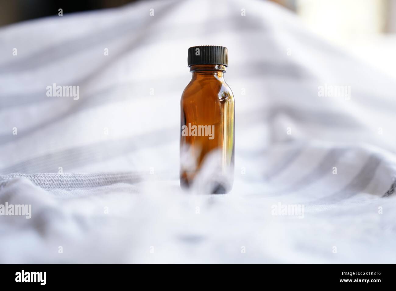 Imitierte, bernsteinfarbene Glasflasche auf weißem Hintergrund Stockfoto