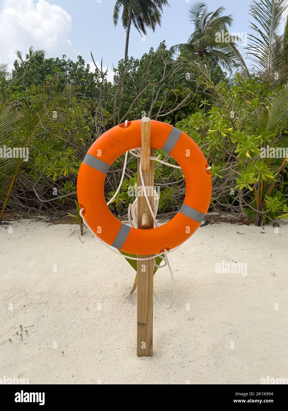 Eine leuchtend orangefarbene Rettungsboje, die für den Notfall auf einer Insel auf den Malediven am Strand platziert wird. Stockfoto