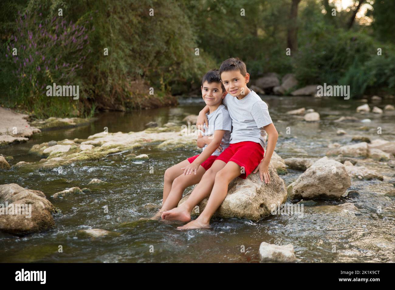 Zwei vereinte Kinder baden im Fluss und blicken auf die Kamera Stockfoto