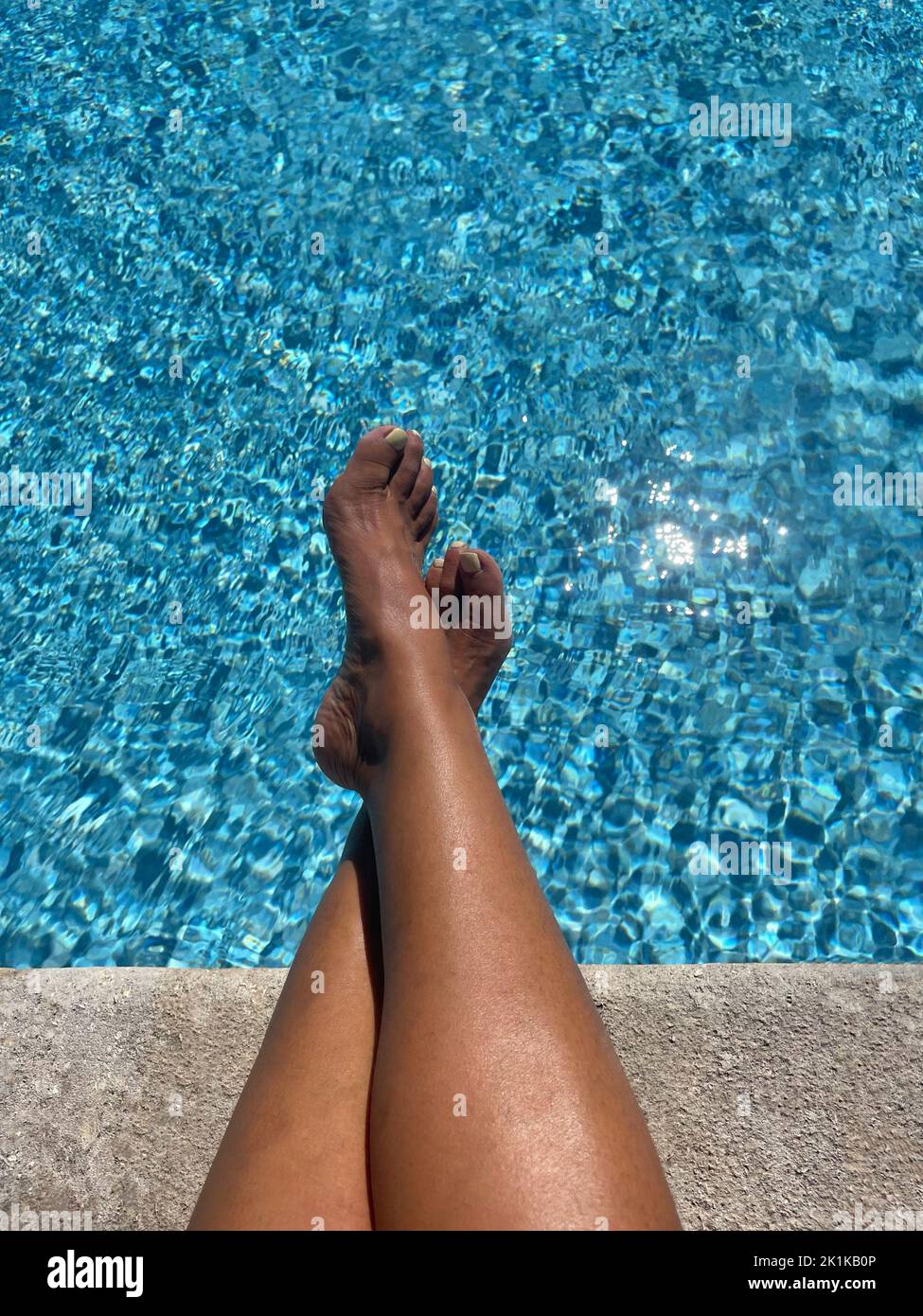 Im Sommer, Frankreich, werden die Beine der Frau von einem Schwimmbad ausgestreckt Stockfoto