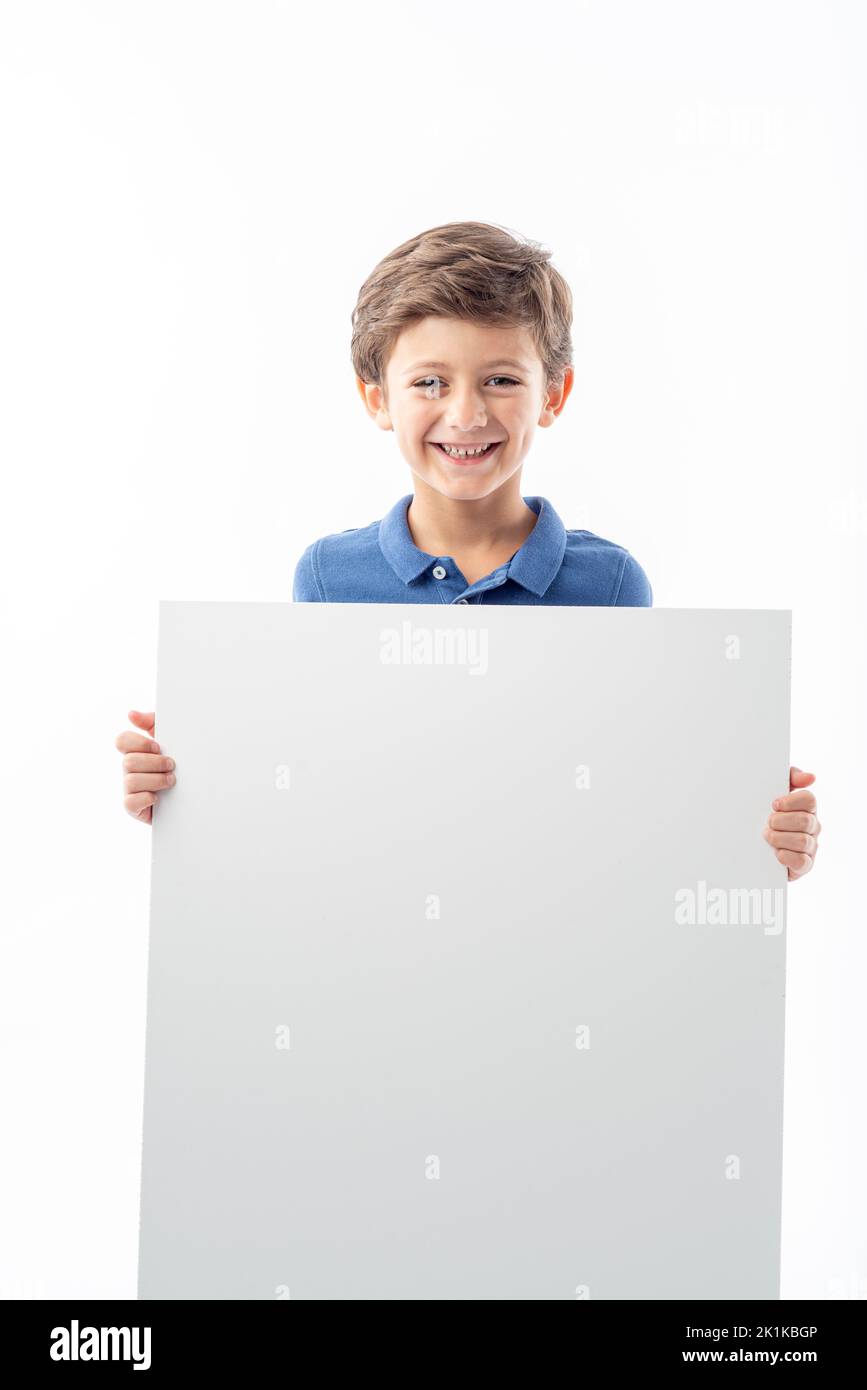Lächelnder kaukasischer Junge, der ein weißes Werbeplakat mit Platz für Text auf weißem Hintergrund zeigt. Stockfoto
