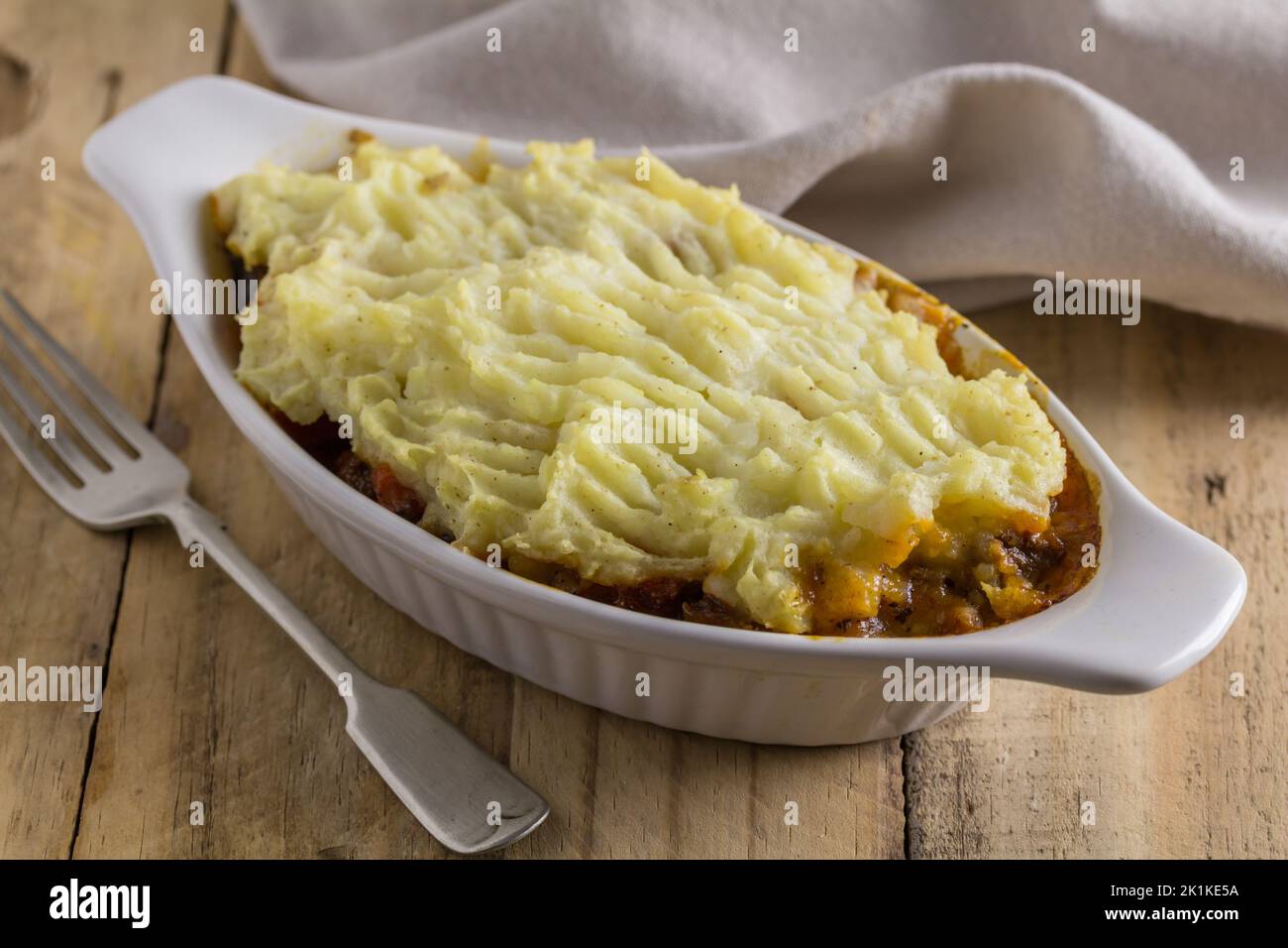 Rustikaler Schafspelzkuchen auf Holztisch - Cottage Pie mit Kartoffelpüree Stockfoto