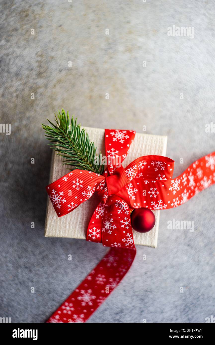 Ansicht von oben auf eine rustikale Geschenkbox mit einem Band gebunden und mit einem Tannenzweig eine Weihnachtskugel dekoriert Stockfoto