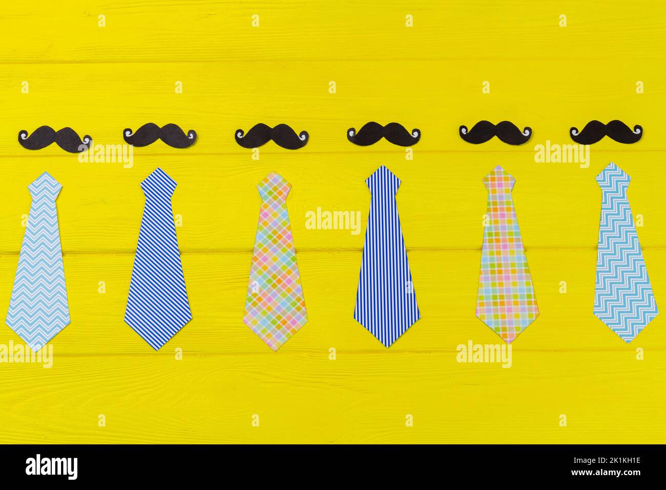 Set von stilvollen Herren Krawatten und Schnurrbärte. Gelber Schreibtisch aus Holz. Stockfoto