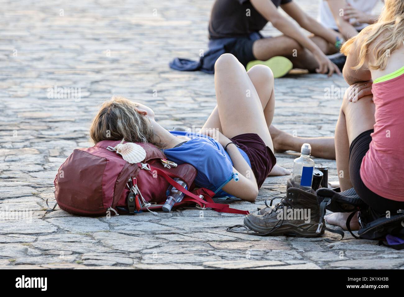 Pilgerin, die sich mit ihrem Rucksack auf dem Obradoiro-Platz ausruhte, nachdem sie nach einem Spaziergang auf dem Jakobsweg in Santiago de Compostela angekommen war. Speicherplatz kopieren Stockfoto