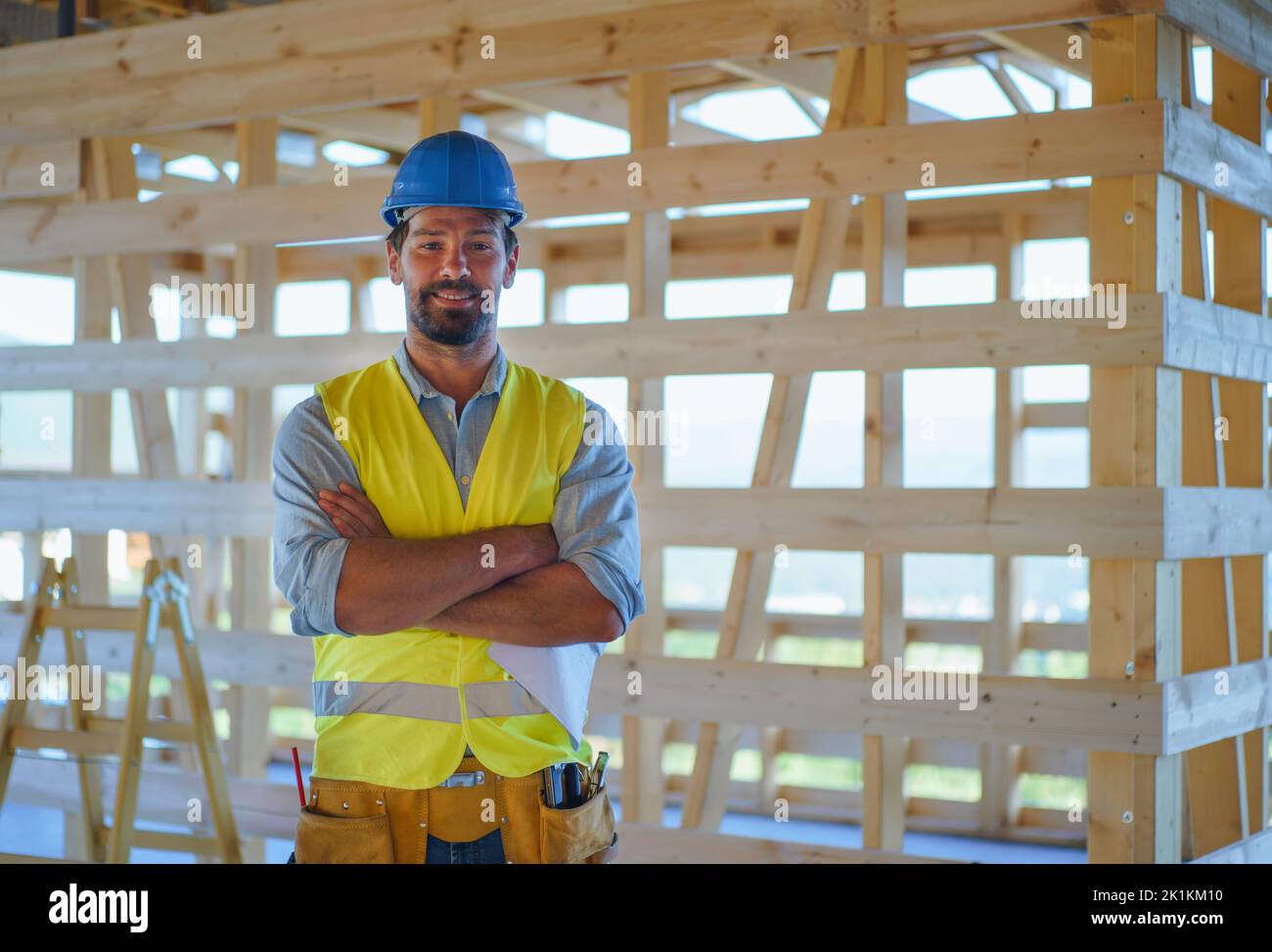 Bauarbeiter in Schutzkleidung posiert auf Öko-Baustelle des Holzrahmenhauses. Stockfoto