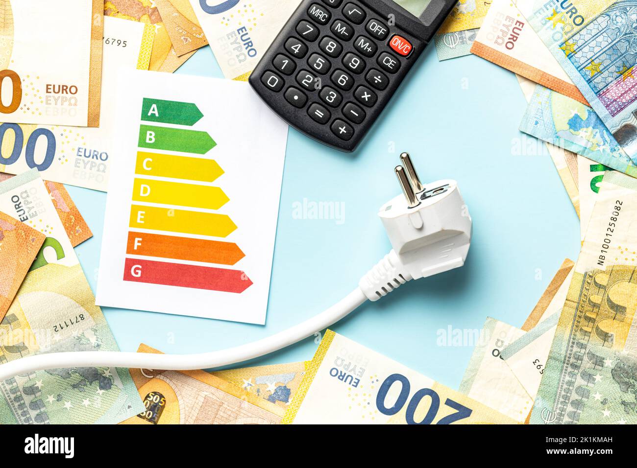 Elektrostecker, Rechner, Energielabel und Euro-Geld auf blauem Hintergrund. Konzept der steigenden Strompreise. Draufsicht. Stockfoto