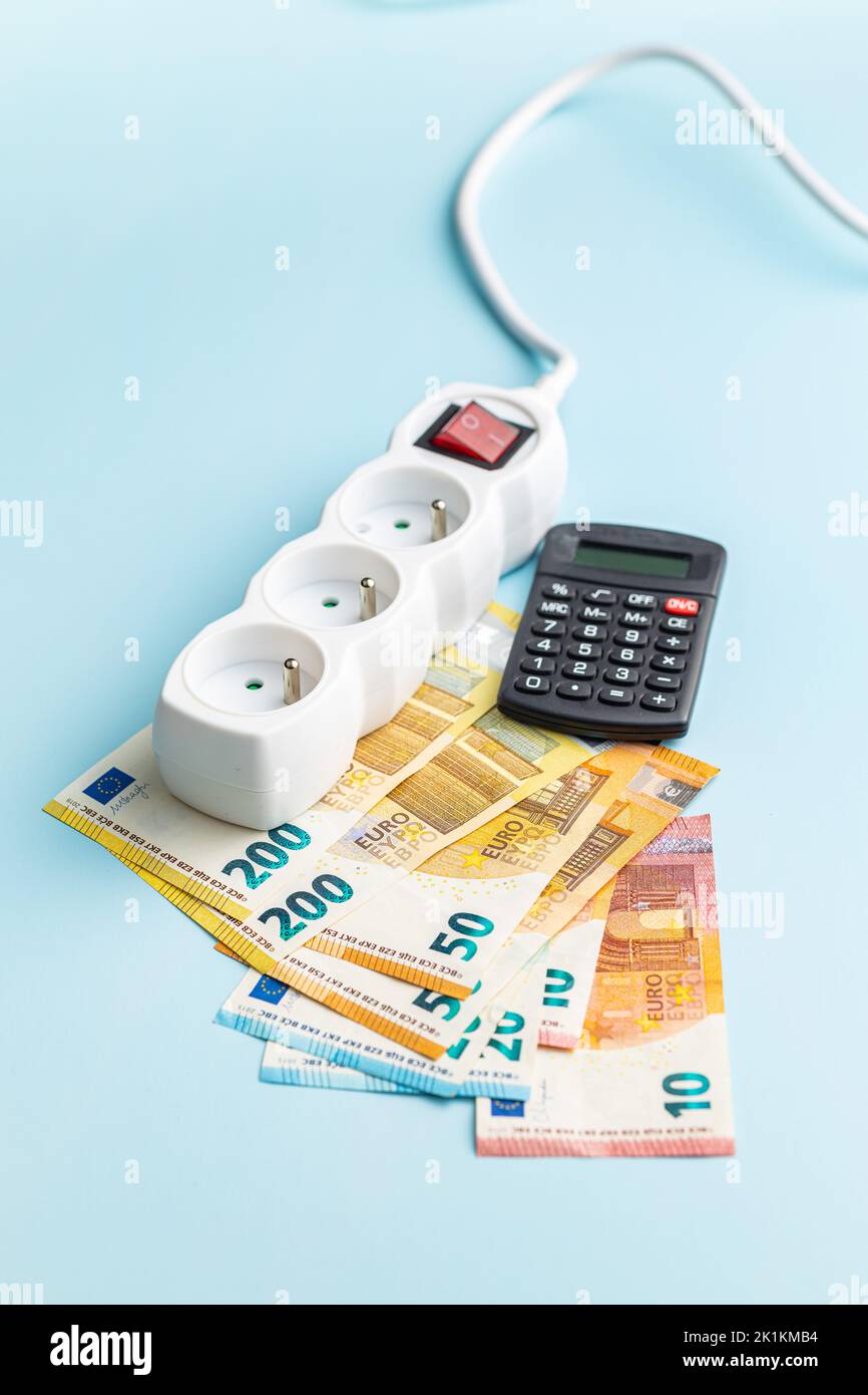 Steckdose, Rechner und Euro-Geld auf blauem Hintergrund. Stockfoto