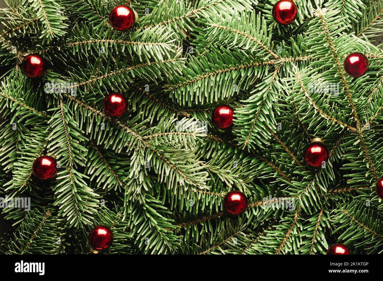 Kreative Weihnachtsferien Hintergrund mit Tannenzweigen und roten weihnachtskugeln Nahaufnahme. Flach liegend, Draufsicht. Frohe Weihnachten Stockfoto