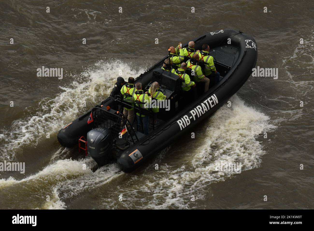 Der Weitwinkel-Blick auf Menschen mit grünen Schwimmwesten im RIB-Schnellboot auf den Wellen Stockfoto