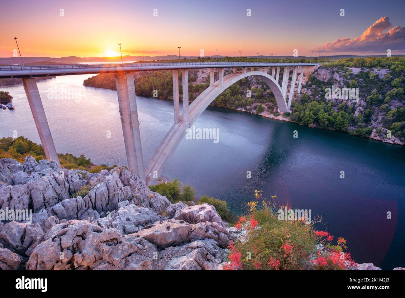 Krka-Brücke, Kroatien. Bild der Betonbogenbrücke Krka-Brücke, die den Krka-Fluss bei Sonnenuntergang überspannt. Stockfoto