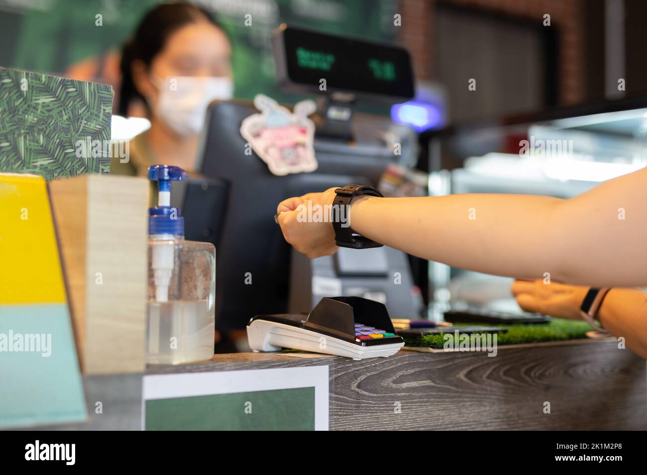 Frau zahlt per Smartwatch mit NFC-Technologie im Café. Stockfoto